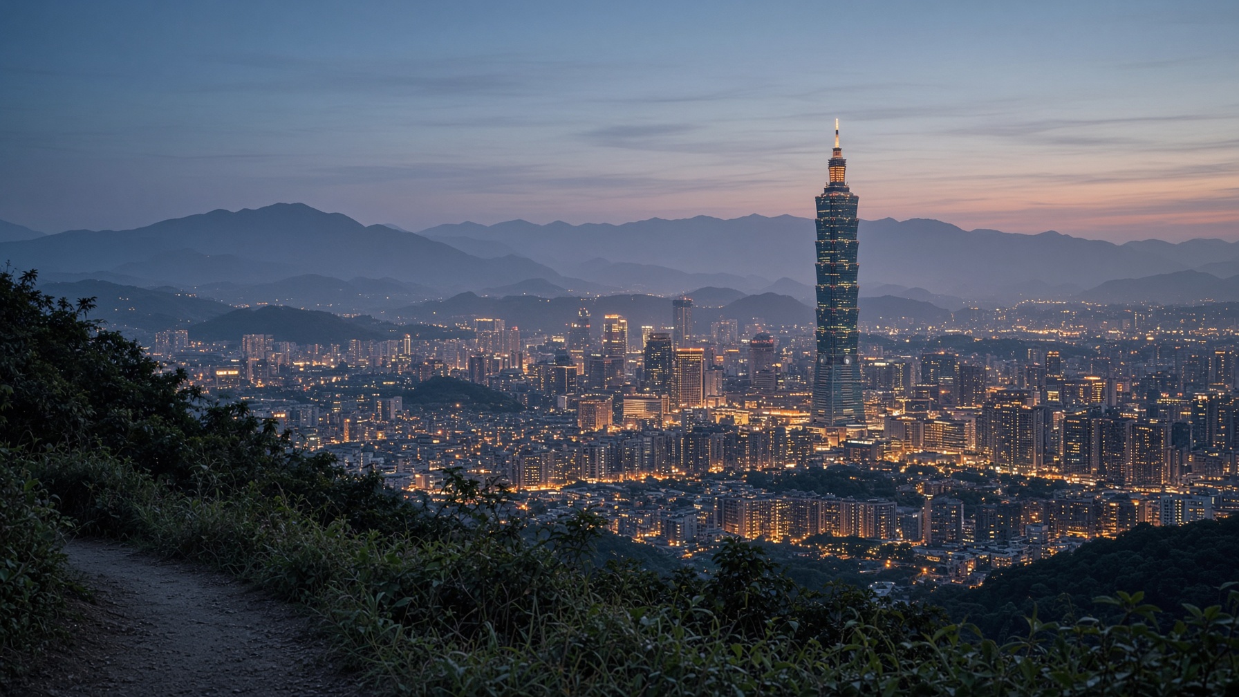 Taipei at blue hour from a hillside, the basin lighting up after the day’s weather